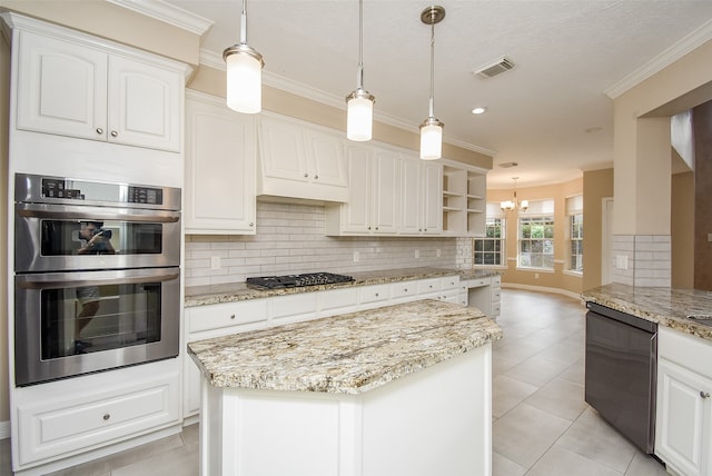 kitchen featuring light stone counters, white cabinets, backsplash, appliances with stainless steel finishes, and decorative light fixtures