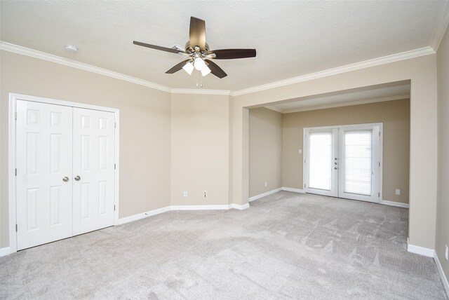 spare room featuring a textured ceiling, ceiling fan, french doors, ornamental molding, and light carpet