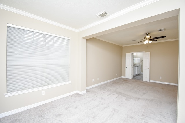 empty room with ceiling fan, light carpet, and crown molding