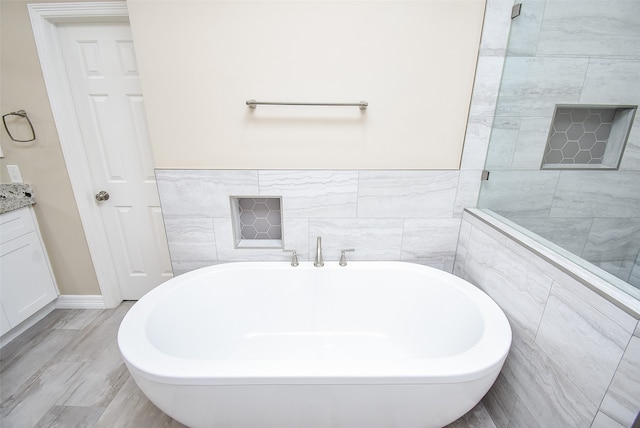 bathroom featuring tile walls, a bath, hardwood / wood-style flooring, and vanity