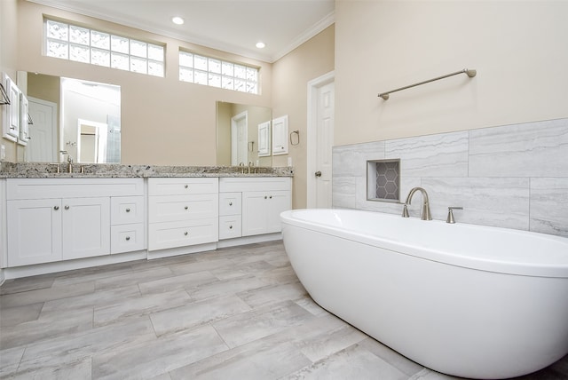 bathroom with a tub to relax in, a healthy amount of sunlight, vanity, and crown molding