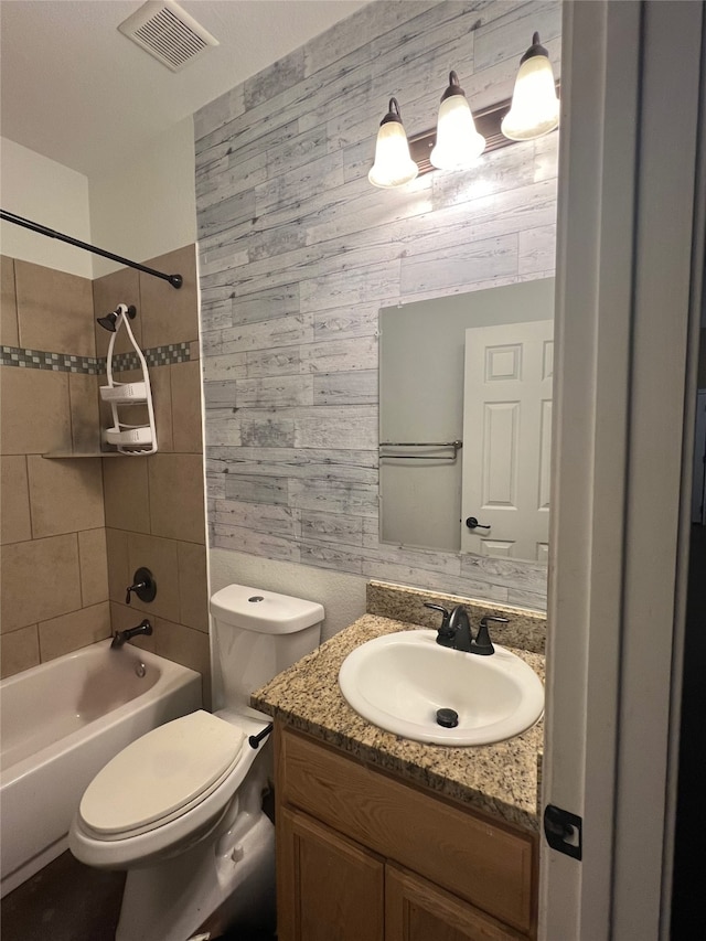 full bathroom with tiled shower / bath, vanity, and toilet