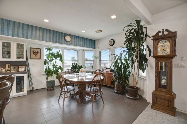 tiled dining area featuring beam ceiling