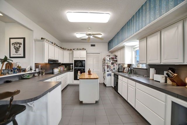 kitchen with white cabinets, ceiling fan, tile flooring, black appliances, and sink