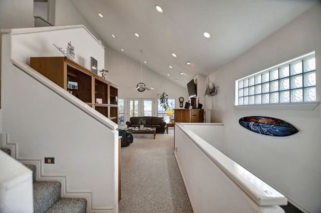 hallway with light carpet and high vaulted ceiling