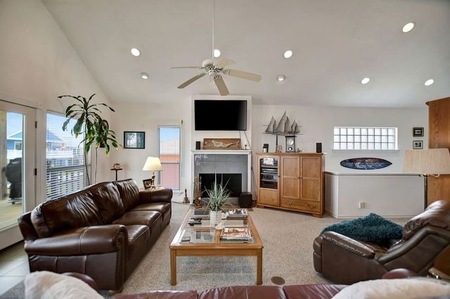 carpeted living room with high vaulted ceiling and ceiling fan