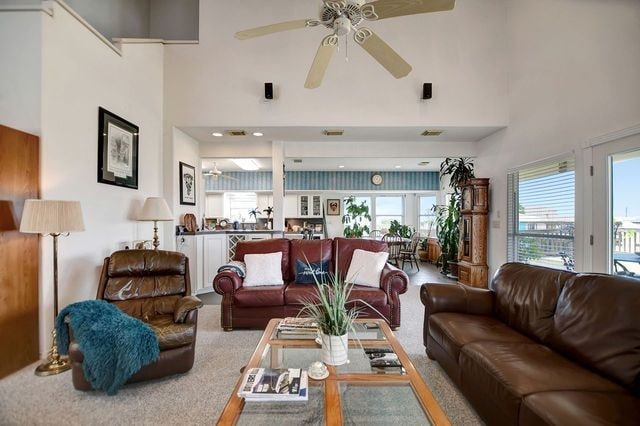 carpeted living room with a towering ceiling and ceiling fan