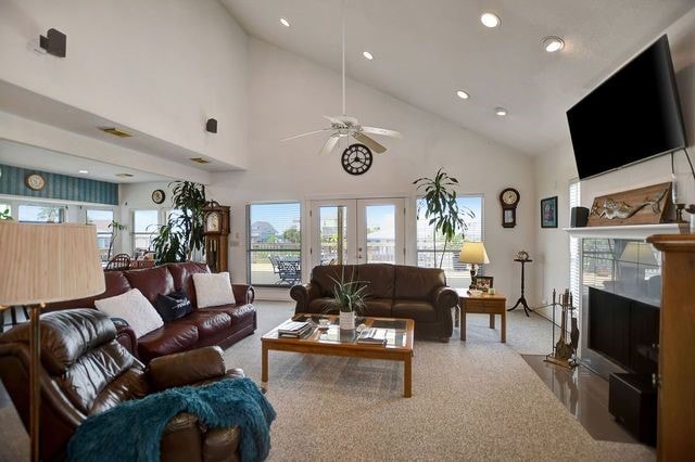 carpeted living room featuring high vaulted ceiling, ceiling fan, and french doors