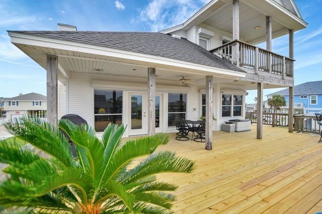 back of property with ceiling fan, a deck, and a balcony