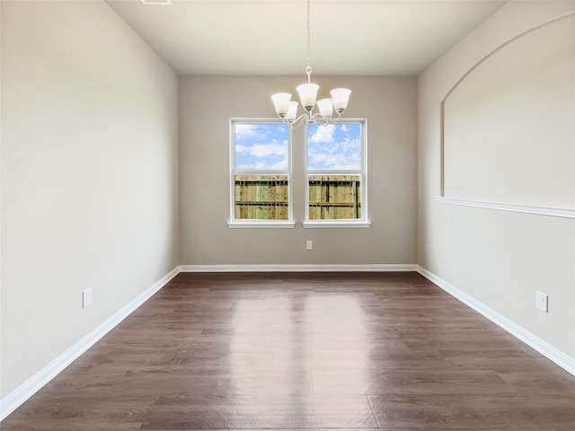 spare room featuring an inviting chandelier and dark hardwood / wood-style flooring