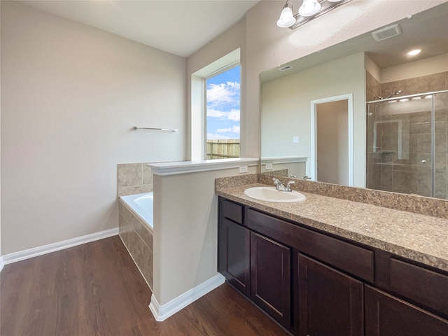 bathroom featuring wood-type flooring, vanity, and plus walk in shower