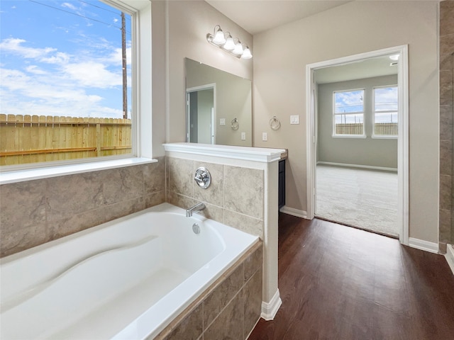 bathroom with wood-type flooring and tiled tub