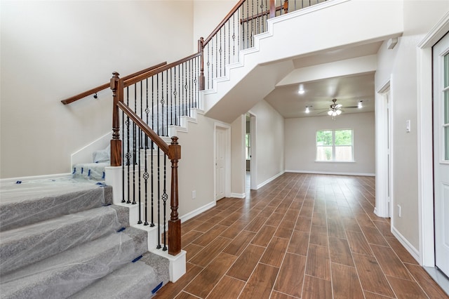 entryway with dark hardwood / wood-style floors, ceiling fan, and a towering ceiling