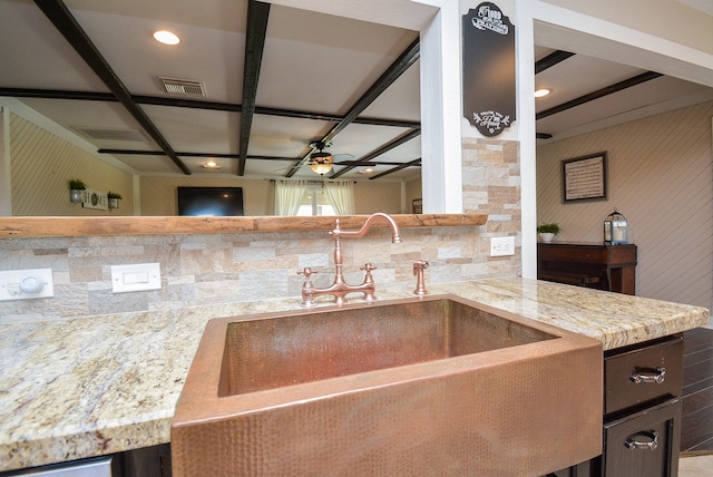 kitchen featuring ceiling fan, tasteful backsplash, dark brown cabinetry, light stone counters, and sink