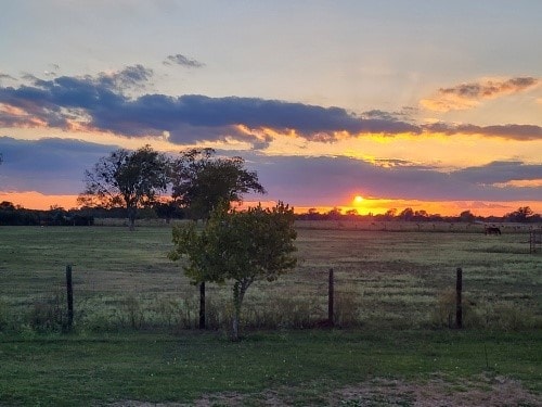 yard at dusk featuring a rural view