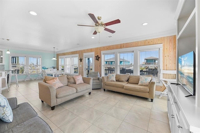 living room featuring wooden walls, ornamental molding, ceiling fan, and light tile flooring