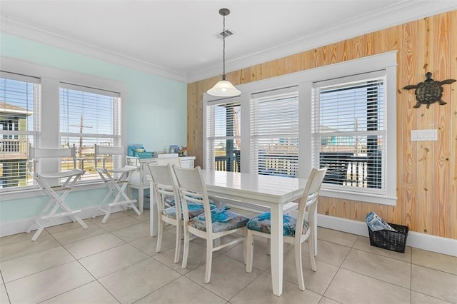 tiled dining room with a healthy amount of sunlight, wooden walls, and crown molding