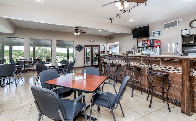 dining room featuring a textured ceiling, french doors, rail lighting, ceiling fan, and light tile floors