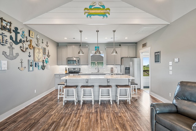 kitchen featuring dark hardwood / wood-style floors, a kitchen island, stainless steel appliances, hanging light fixtures, and tasteful backsplash