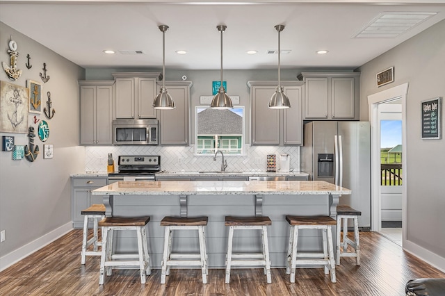 kitchen with a kitchen island, dark hardwood / wood-style flooring, appliances with stainless steel finishes, decorative light fixtures, and sink