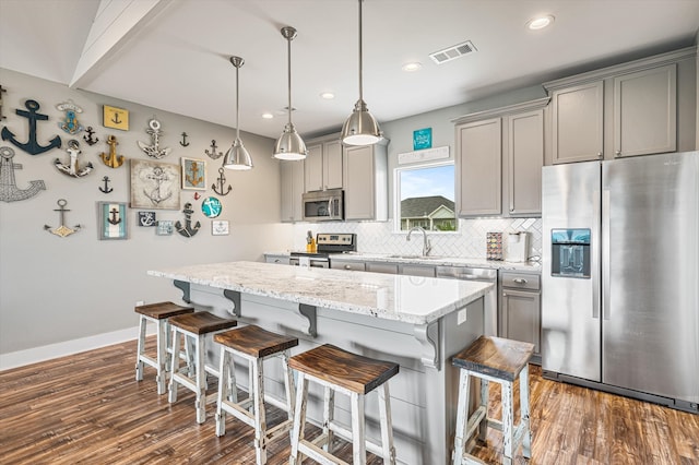 kitchen with a center island, hanging light fixtures, dark hardwood / wood-style flooring, stainless steel appliances, and tasteful backsplash