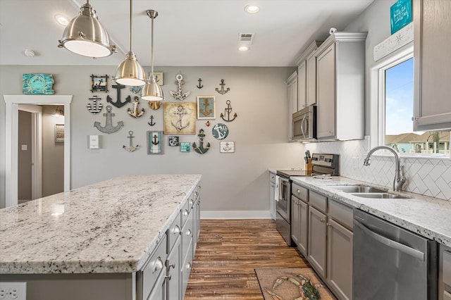 kitchen with dark wood-type flooring, appliances with stainless steel finishes, gray cabinets, backsplash, and sink