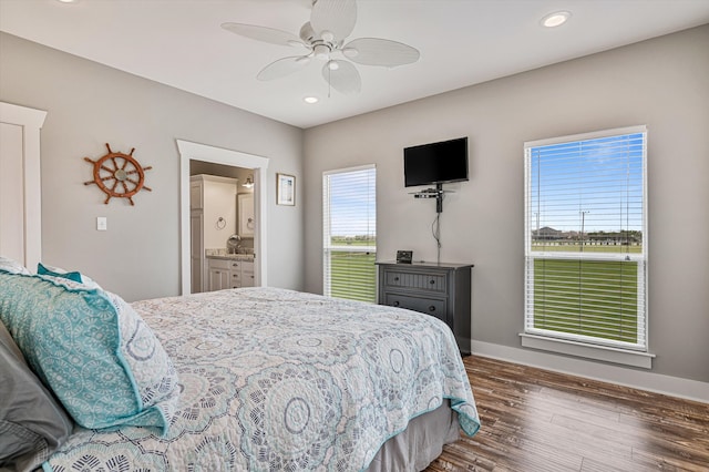 bedroom with connected bathroom, ceiling fan, dark hardwood / wood-style floors, and multiple windows