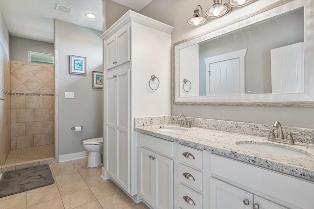 bathroom featuring double sink, a tile shower, tile floors, toilet, and large vanity