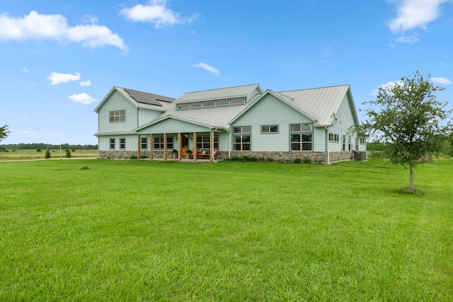 back of house featuring covered porch, solar panels, a yard, and central air condition unit