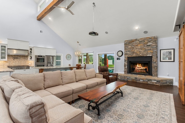 living room with beam ceiling, a stone fireplace, high vaulted ceiling, hardwood / wood-style floors, and ceiling fan with notable chandelier