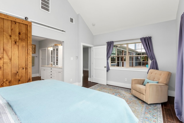 bedroom featuring high vaulted ceiling, a barn door, dark wood-type flooring, and connected bathroom