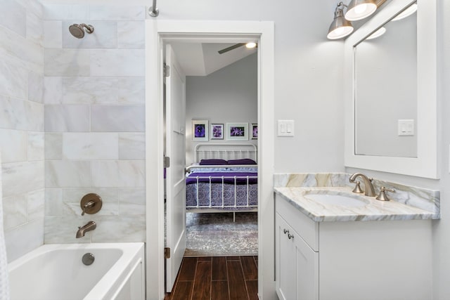 bathroom featuring tiled shower / bath combo, ceiling fan, wood-type flooring, and vanity