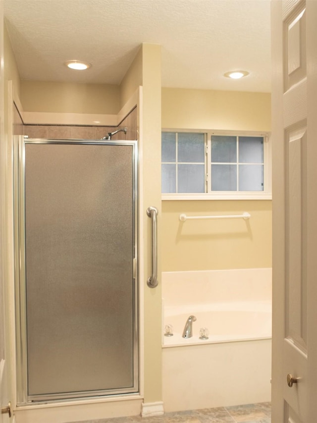 bathroom featuring plus walk in shower and a textured ceiling