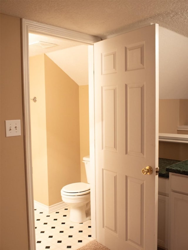 bathroom with a textured ceiling, vanity, and toilet