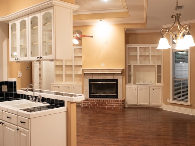 kitchen featuring sink, tile countertops, dark hardwood / wood-style floors, white cabinetry, and hanging light fixtures