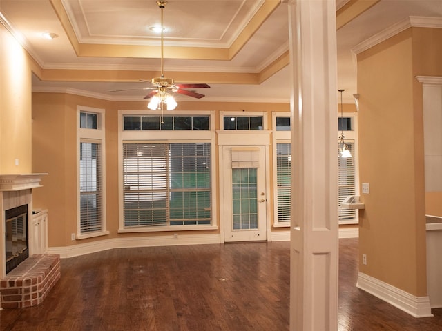 unfurnished living room with a brick fireplace, crown molding, ceiling fan, and dark wood-type flooring