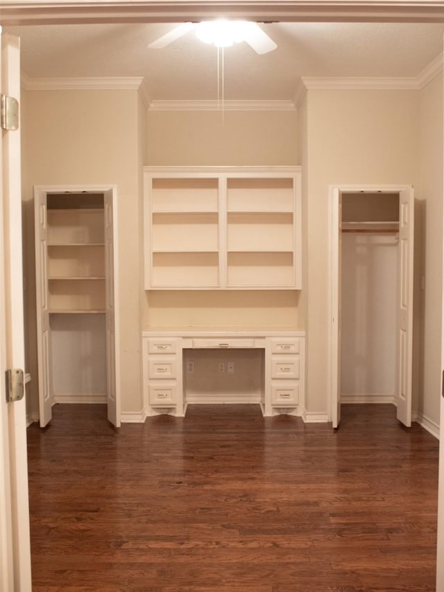 interior space with ceiling fan, built in desk, dark hardwood / wood-style floors, and ornamental molding