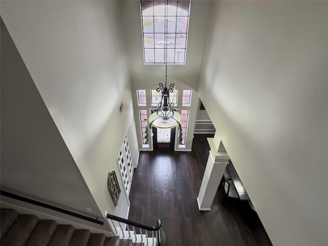 foyer entrance with a healthy amount of sunlight, an inviting chandelier, a towering ceiling, and dark hardwood / wood-style flooring