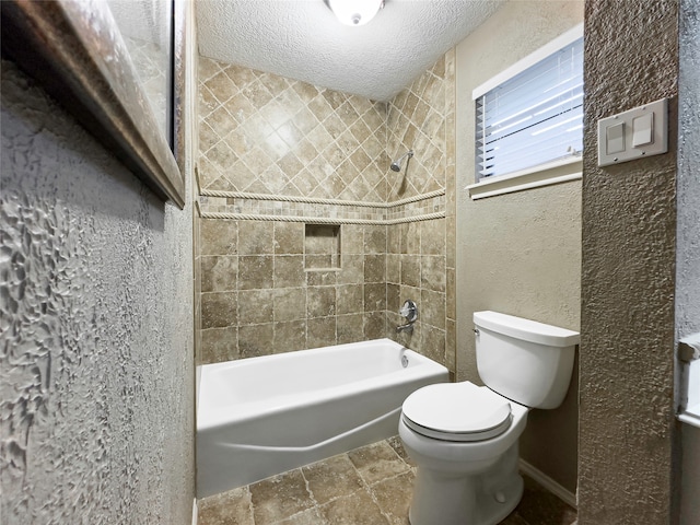 bathroom with tile floors, a textured ceiling, tiled shower / bath combo, and toilet