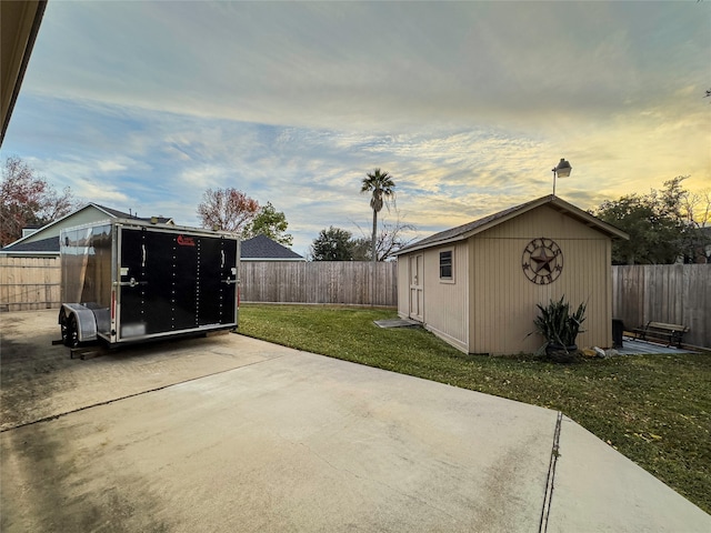 patio terrace at dusk featuring a yard and a storage unit