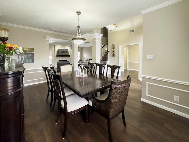 dining space with dark wood-type flooring, ornamental molding, and decorative columns