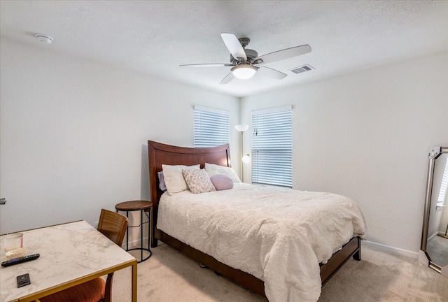 bedroom featuring ceiling fan, a textured ceiling, and light colored carpet