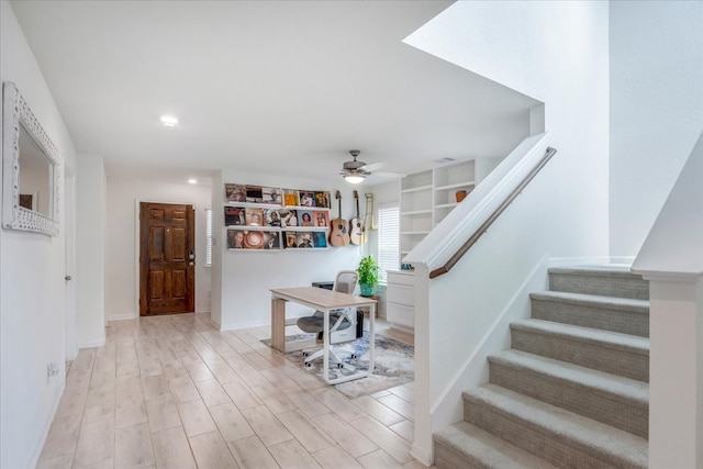 stairway with hardwood / wood-style floors and ceiling fan