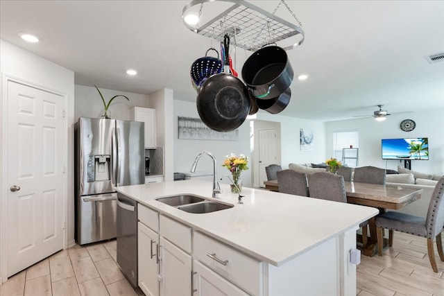 kitchen with a center island with sink, white cabinetry, appliances with stainless steel finishes, sink, and light hardwood / wood-style floors