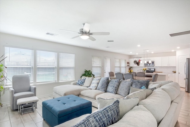 living room featuring light hardwood / wood-style floors, a healthy amount of sunlight, and ceiling fan