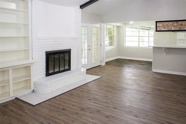 unfurnished living room featuring brick wall, a brick fireplace, lofted ceiling with beams, and dark hardwood / wood-style floors