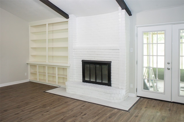 unfurnished living room with french doors, a fireplace, brick wall, dark hardwood / wood-style flooring, and beam ceiling