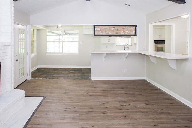 unfurnished living room featuring sink, dark hardwood / wood-style floors, and lofted ceiling