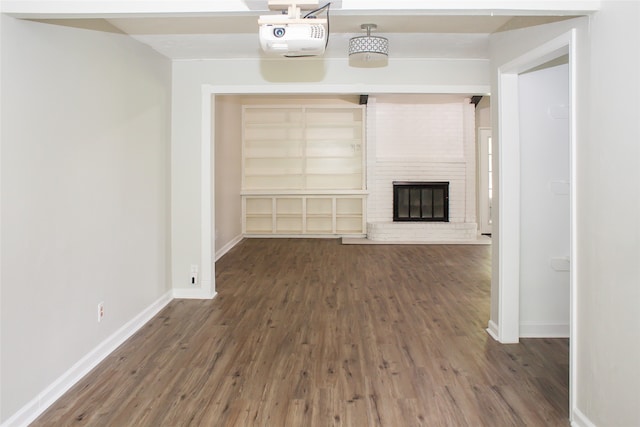 unfurnished living room with a brick fireplace and dark hardwood / wood-style floors