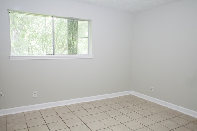 empty room with a healthy amount of sunlight and light tile floors